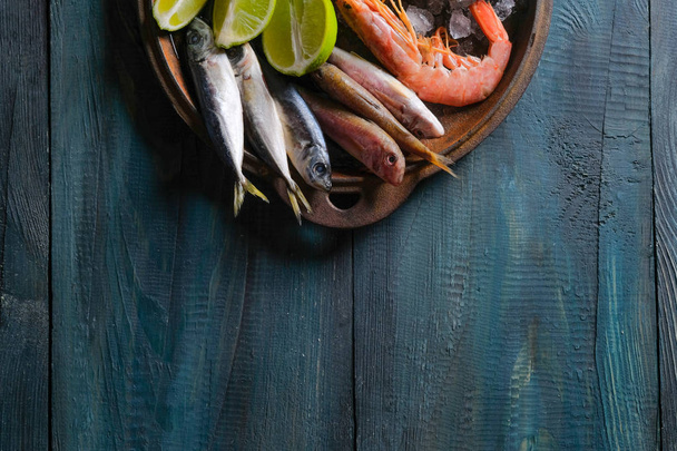 close-up of seafood set of shrimp and fish with lime in plate on wooden table background  - Фото, зображення