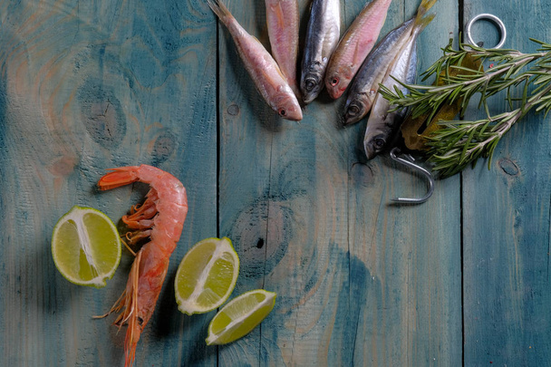 close-up de frutos do mar conjunto de camarão e peixe com limão e alecrim sobre fundo de mesa de madeira
  - Foto, Imagem