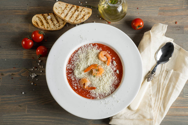 Tomato soup with croutons bread and shrimps on a wooden grey kitchen table - Foto, imagen