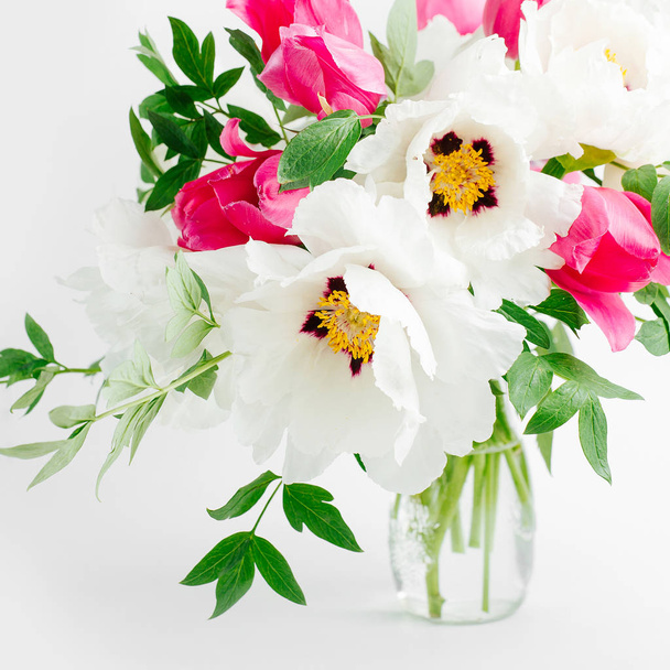 Bouquet of white peonies and pink tulips in glass vase on white background - Foto, Bild
