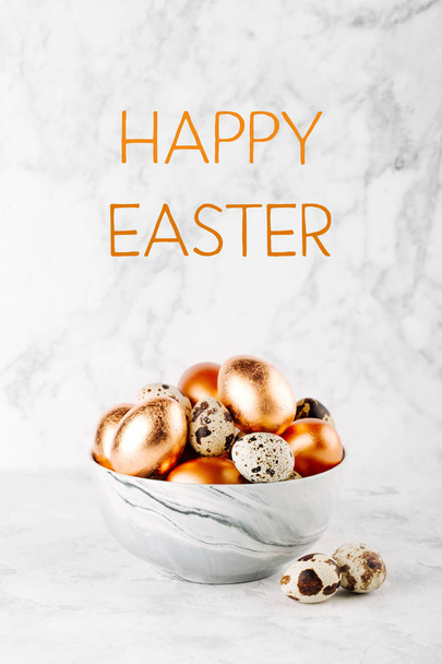 Bowl with painted copper eggs and quail Easter eggs on marble background - 写真・画像