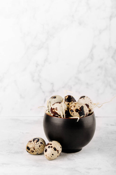 Black bowl with quail eggs on marble background - Fotografie, Obrázek