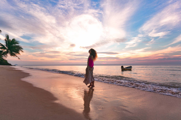 jonge vrouw silhouet op het strand bij zonsondergang - Foto, afbeelding