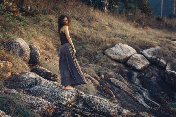 夕暮れ時の岩の上に美しい女性 - 写真・画像