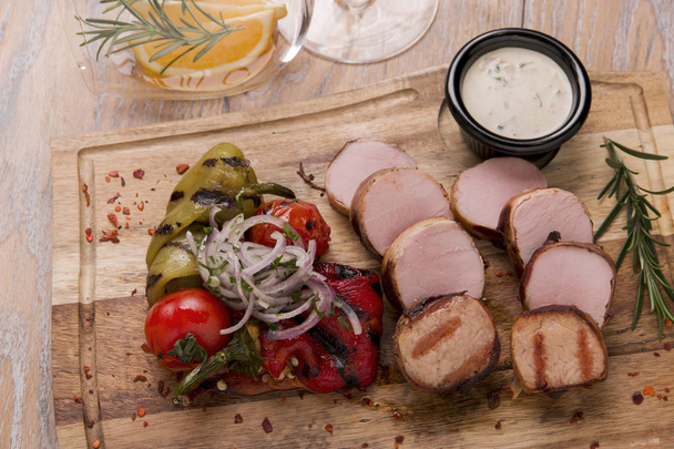 Bistecche di maiale tagliate alla griglia su una tavola di legno con verdure
 - Foto, immagini