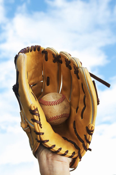 une personne attrapant une balle de baseball avec un gant
 - Photo, image