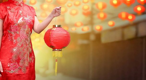 женщина держит китайские новогодние фонари в китайском городе
 - Фото, изображение