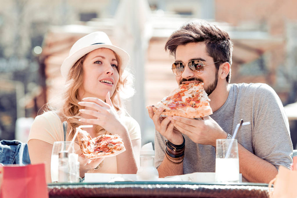 Весела молода пара сидить у ресторані, їсть піцу
. - Фото, зображення