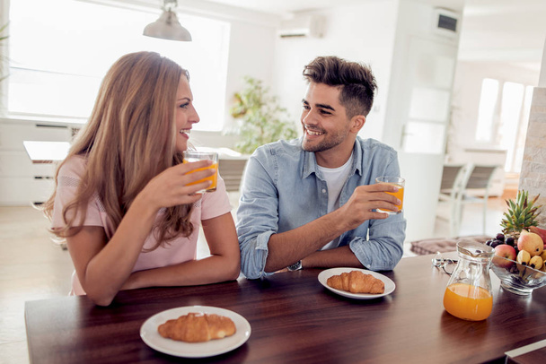 Cheerful couple having breakfast in the kitchen. - Photo, Image