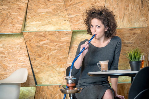 Trendy hipster girl enjoying hookah at a modern coffee shop - Photo, image