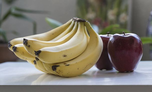Bananen und Äpfel auf dem Tisch. Frontalansicht, regelmäßiger Winkel. - Foto, Bild