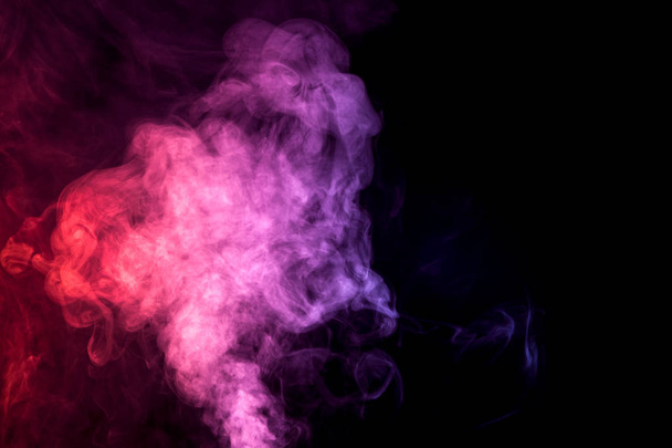 Dikke kleurrijke rook van purle en roze op een geïsoleerde zwarte achtergrond. Achtergrond van de rook van vape - Foto, afbeelding