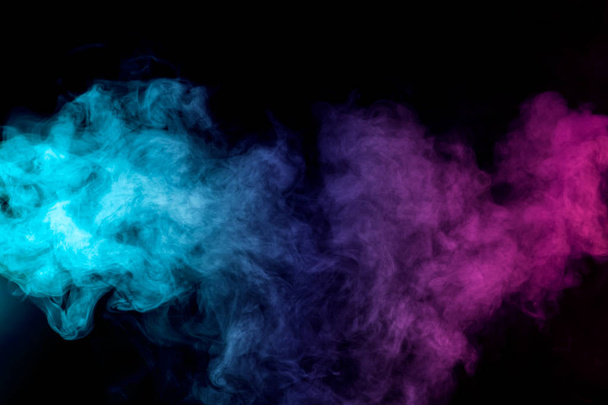 Dense multicolored smoke of   red, purple and pink colors on a black isolated background. Background of smoke vape - Photo, Image