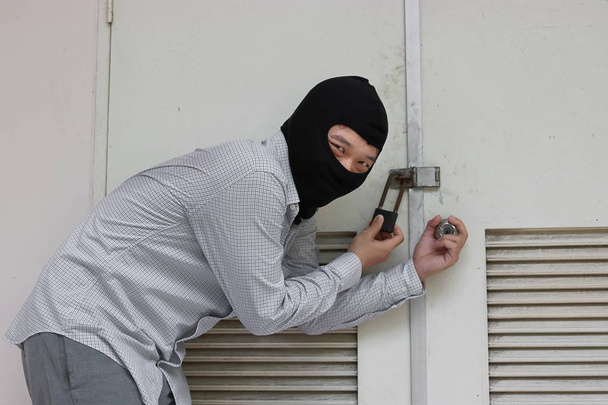 Ladrão mascarado usando uma balaclava escapando depois de esgueirar-se para dentro da casa. Conceito de crime
 - Foto, Imagem