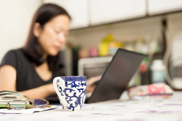 Vybrané zaměření kávy šálek žena pracující s počítačem doma - Fotografie, Obrázek