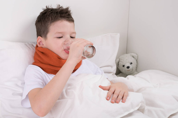 αγόρι στο κρεβάτι πόσιμο νερό μετά τη λήψη ιατρικής - Φωτογραφία, εικόνα