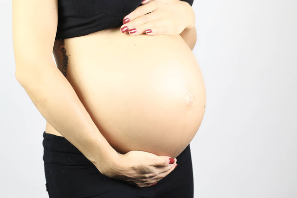 Primo piano ripresa in studio di donna incinta toccare la pancia. isolato su sfondo bianco
 - Foto, immagini
