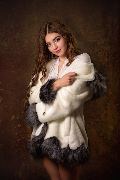Preciosa joven posando en lujoso abrigo de piel y body. Moda, belleza. Captura de estudio
. - Foto, Imagen