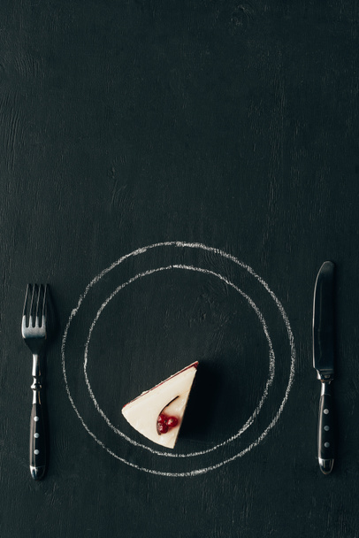 top view of piece of cake and cutlery on black tabletop - Foto, imagen