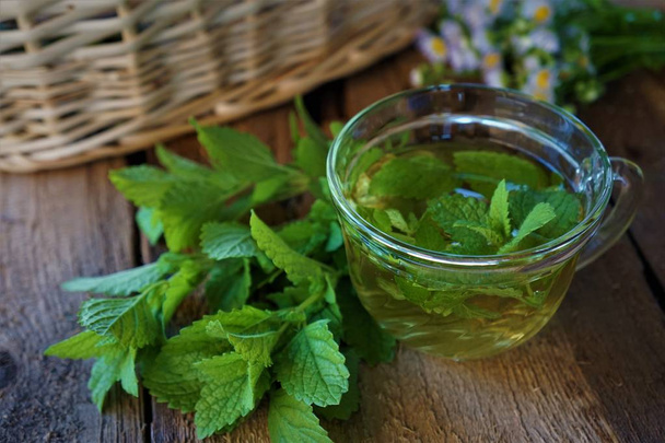 Lemon balm hot herbs tea with fresh leaves on wooden background - Photo, Image