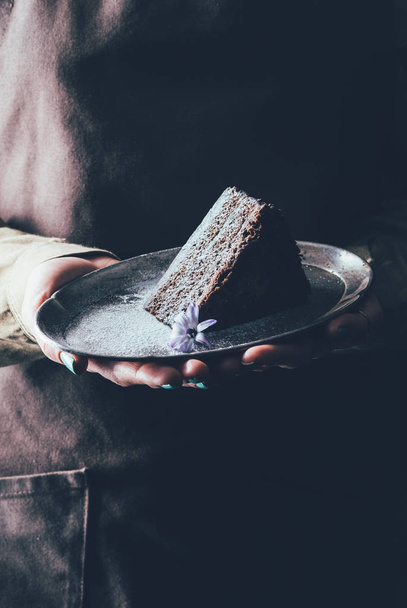 close up view of woman holding piece of homemade cake on plate in hands - Foto, imagen