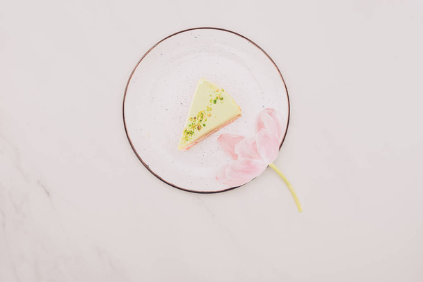 Tortenstück von oben auf Teller und Blume auf weißer Oberfläche - Foto, Bild