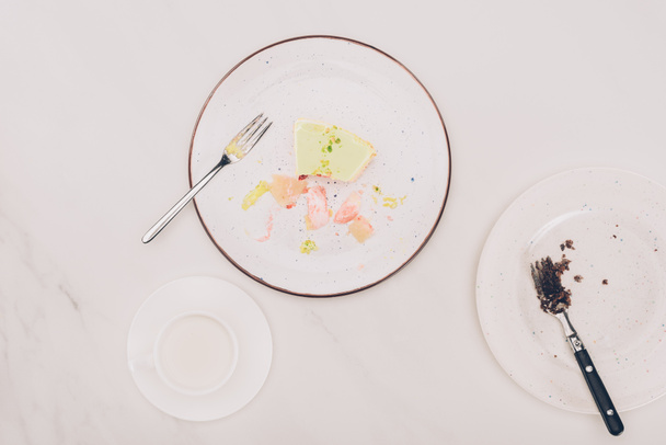 вид сверху на кусочки торта на тарелках с вилками и чашкой молока на столе
 - Фото, изображение