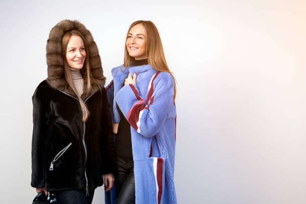 毛皮ミンク ポーズから黒と裸の毛皮のコートで 2 人の若い美しい女性ホワイト分離バック グラウンド - 写真・画像