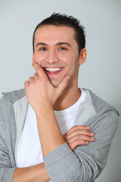 Gros plan de jeune homme souriant avec la main sur le menton
 - Photo, image