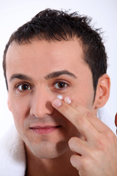 Closeup of young man putting moisturizer on his face - Photo, Image