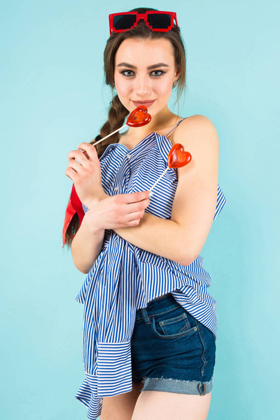 Szczęśliwy Ładna brunetka dziewczynka gospodarstwa dwa serca kształcie lizaki na tle niebieski studio  - Zdjęcie, obraz