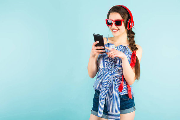 hübsches brünettes Mädchen in modernen Kopfhörern mit ihrem Smartphone - Foto, Bild