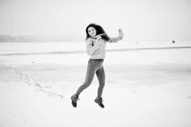 Funny jumping girl on frozen lake in winter day. - Photo, Image