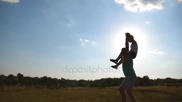 Батько і син грають на полі на заході сонця. Маленький хлопчик сидить на плечах свого тата, ходячи в красивому пейзажі. Щаслива сім'я проводить час на відкритому повітрі. Активний спосіб життя. Повільний рух
 - Кадри, відео