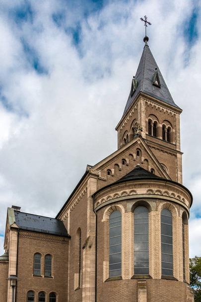 Kerk met hoge torenspits en kruis op de top - Foto, afbeelding