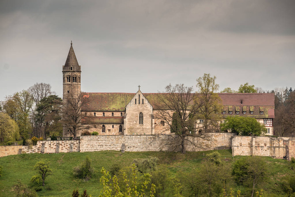 Vanha keskiaikainen luostari, jonka ympärillä on isot muurit
 - Valokuva, kuva