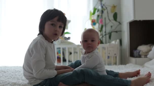 Little toddler boy, playing with his little brother at home in bedroom - Materiał filmowy, wideo