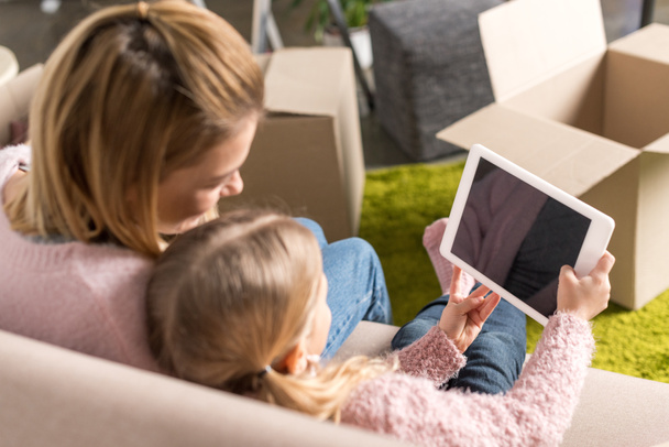 mère et fille utilisant une tablette numérique avec écran vierge tout en déménageant à la maison
  - Photo, image