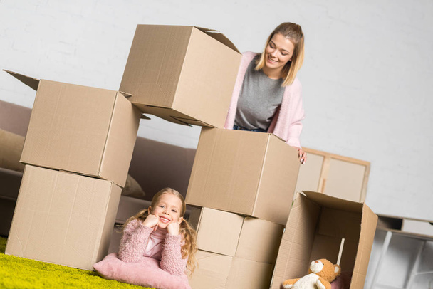 μητέρα και κόρη διασκέδαση με κουτιά από χαρτόνι, ενώ κινείται σπίτι - Φωτογραφία, εικόνα