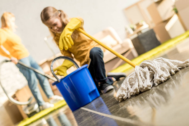 cute little girl with mop and bucket cleaning new apartment - Foto, Bild