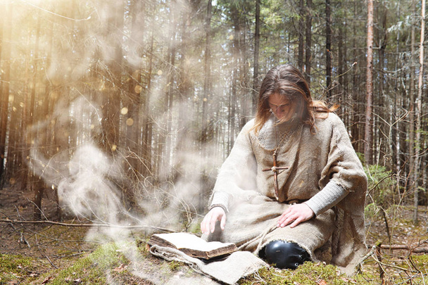 Un hombre en una sotana pasa un ritual en un bosque oscuro
 - Foto, Imagen