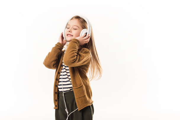 joyful little child listening music with headphones isolated on white - 写真・画像