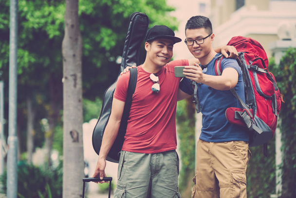 Радісний в'єтнамських друзів з зубастий усмішками позують для selfie беручи Прогулянка в центр міста - Фото, зображення