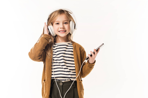 adorable little child listening music with headphones and smartphone isolated on white - Φωτογραφία, εικόνα