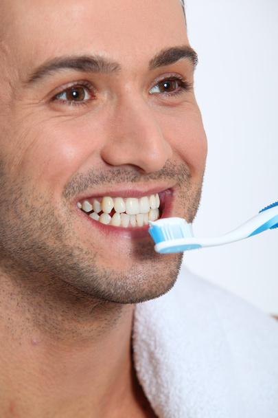 Closeup of young man brushing his teeth - Foto, afbeelding