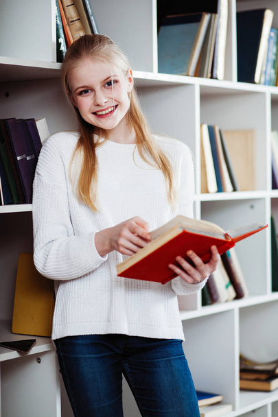 Teenage girl in a library - Фото, изображение