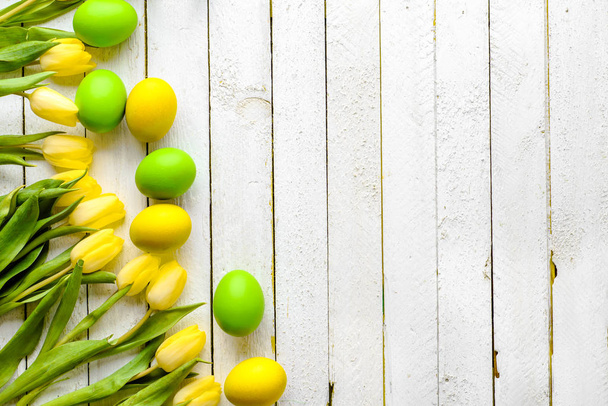 Easter background, spring easter eggs and tulips on wooden table, top view - Photo, image