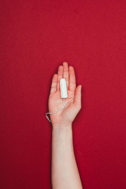 cropped shot of woman holding tampon in hand isolated on red - Photo, Image