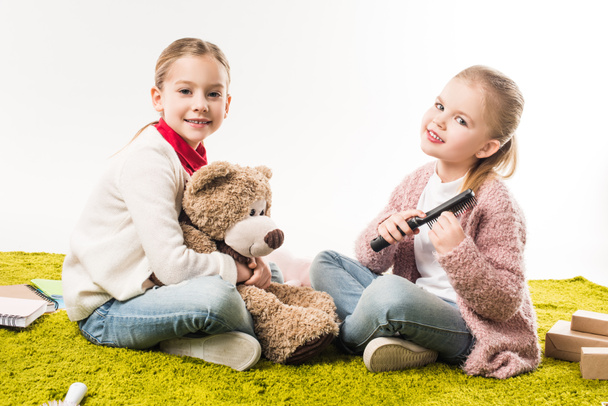 little sisters spending time together while sitting on floor isolated on white - Foto, Bild