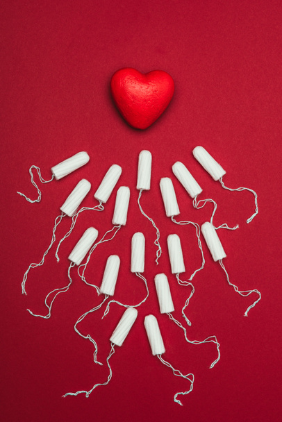 top view of arranged menstrual tampons and red heart isolated on red - Zdjęcie, obraz